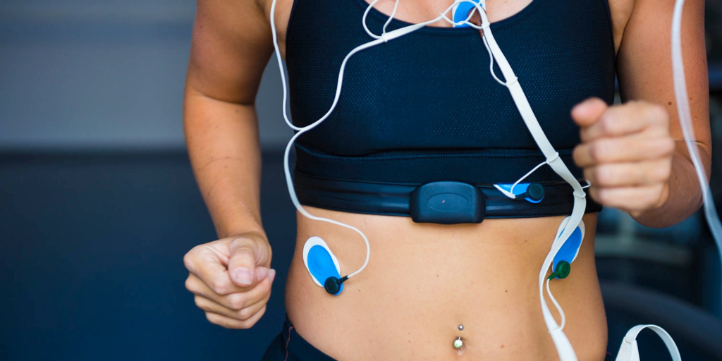 Person running on a treadmill wearing electrodes for a medical fitness test.